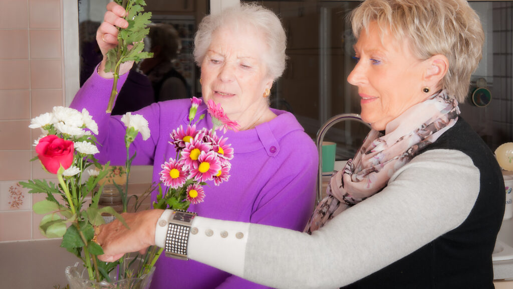 Fiona Lowry, Founder of The Good Care Group, arranging flowers with a care home resident