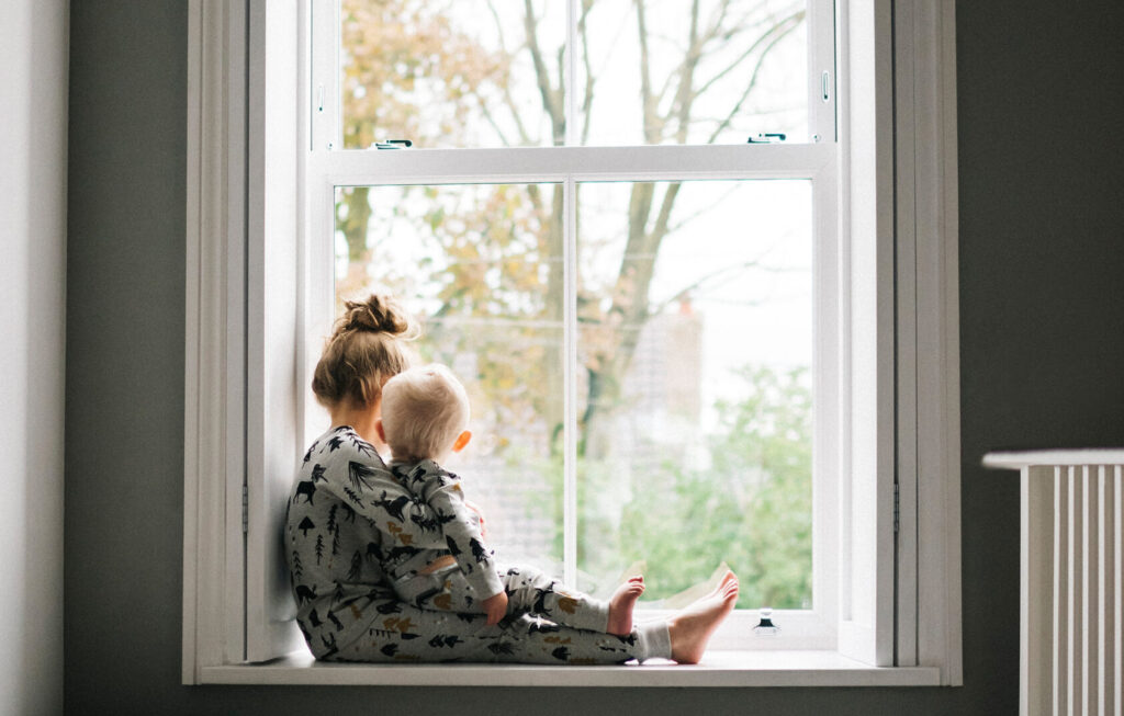 Two children sat on a window sill